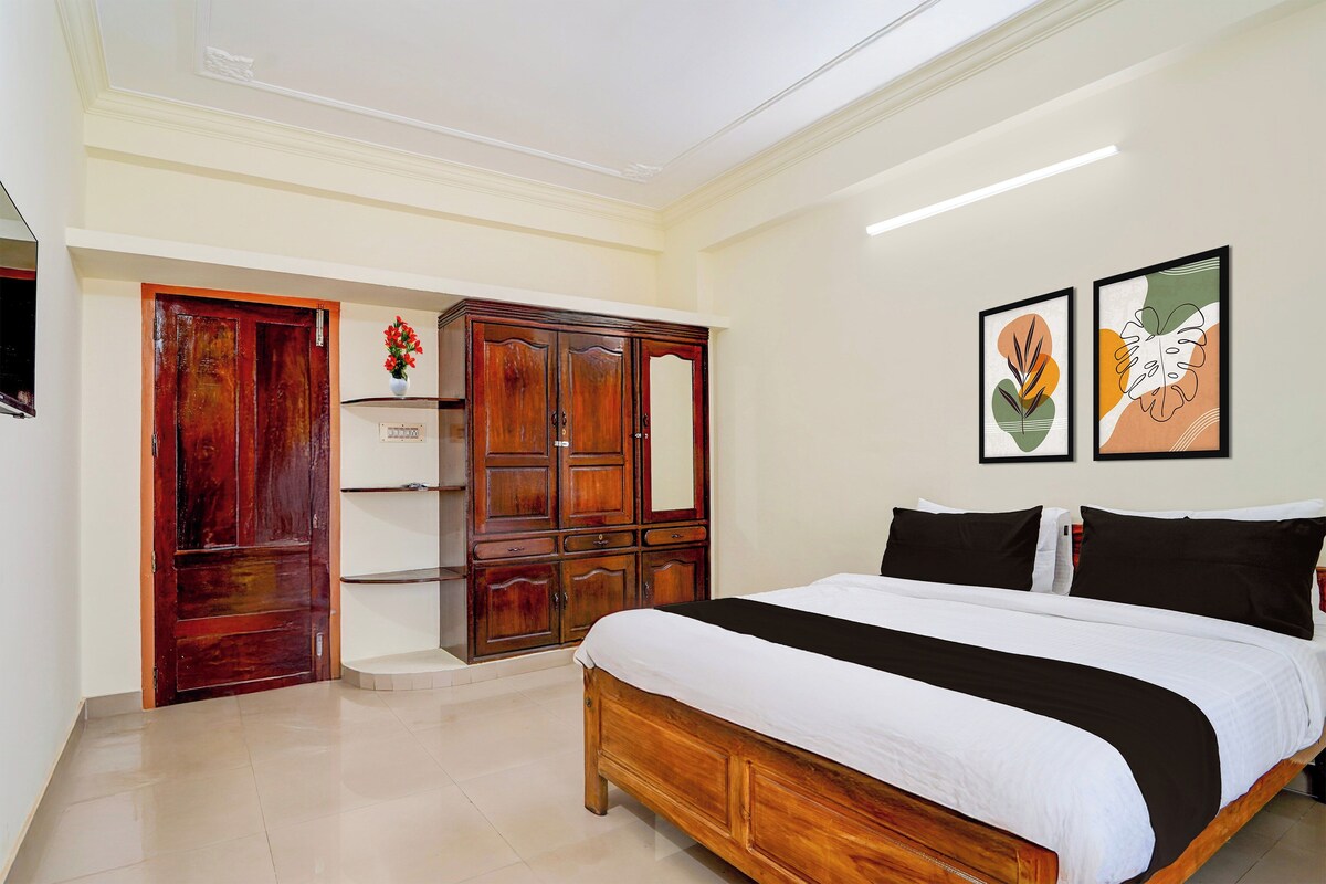 A bedroom with a wooden bed, a wardrobe, and two framed artworks on the wall.