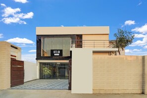 A modern hotel entrance with a glass door, a metal gate, and a clear sky. - Super OYO Hotel O Ayodhya Dham Bus (Ayodhya)