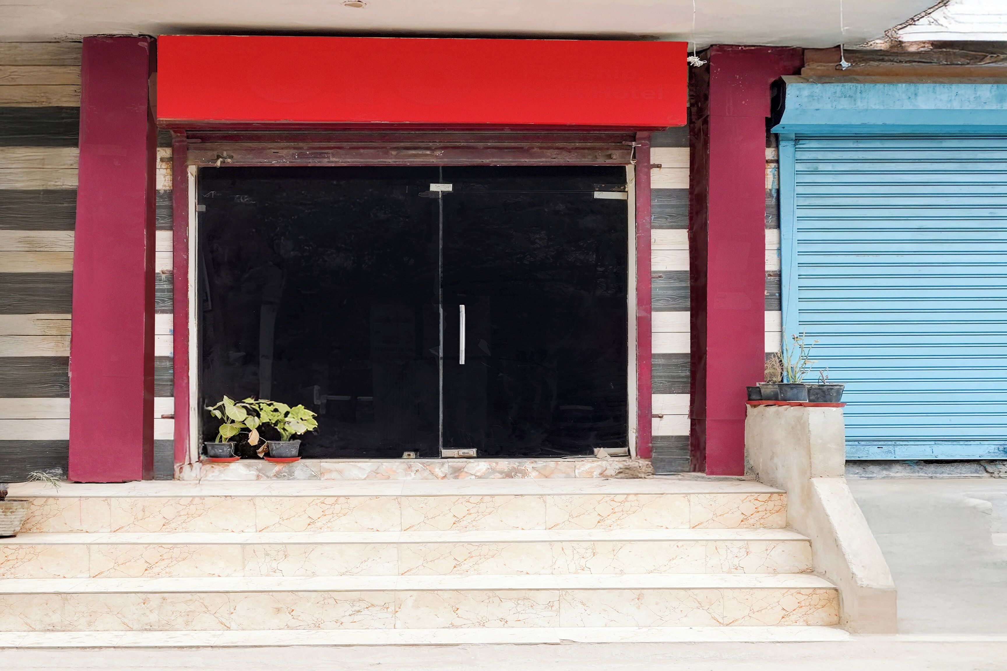 A building entrance with a red awning, a black door, and a set of marble steps leading up to it.