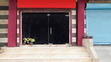 A building entrance with a red awning, a black door, and a set of marble steps leading up to it.