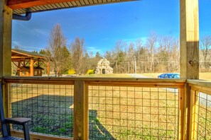 A wooden deck with a view of a fenced area and a stone structure. - Peaceful Cosby Retreat - Hot Tub, Grill, and More! (Cosby)