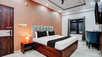 Habitación de hotel con una cama de madera, una mesita de noche con lámpara, un ventilador de techo y una ventana con cortinas.