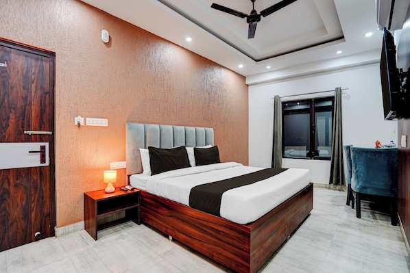 A hotel room with a wooden bed, a nightstand with a lamp, a ceiling fan, and a window with curtains.