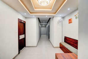 A hallway with a wooden door, a bench, and a ceiling light fixture.