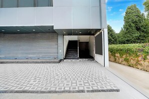 A modern building with a closed garage door, a staircase leading to an entrance, and a patterned pavement.