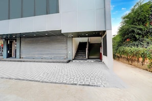 A modern building with a covered entrance, a staircase leading to an upper level, and a patterned pavement. - Collection O Kotdwar Railway Junction (Kotdwāra)