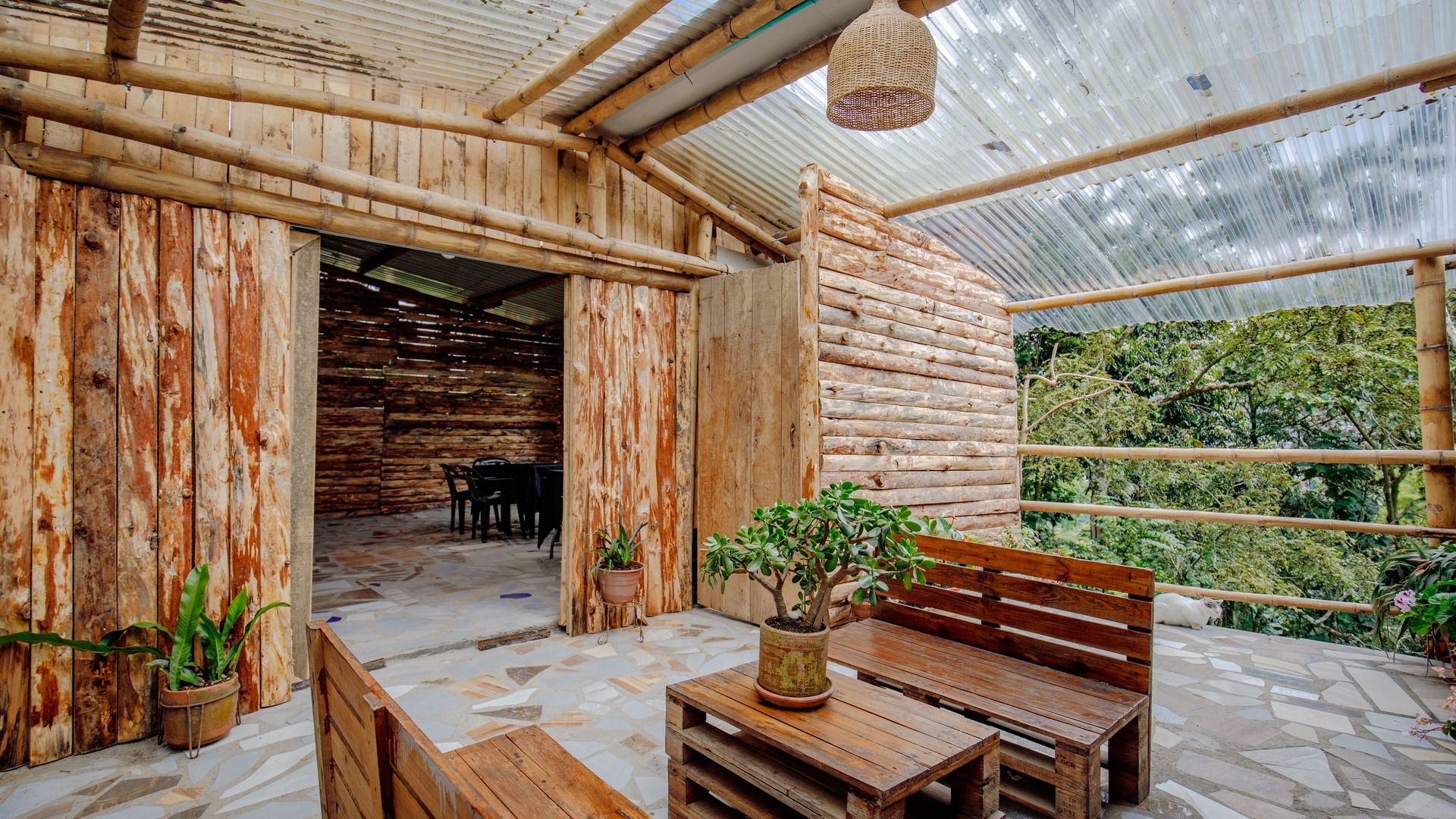 An indoor space with a wooden exterior, a tiled floor, and a bench with a potted plant.