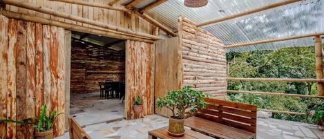 An indoor space with a wooden exterior, a tiled floor, and a bench with a potted plant.
