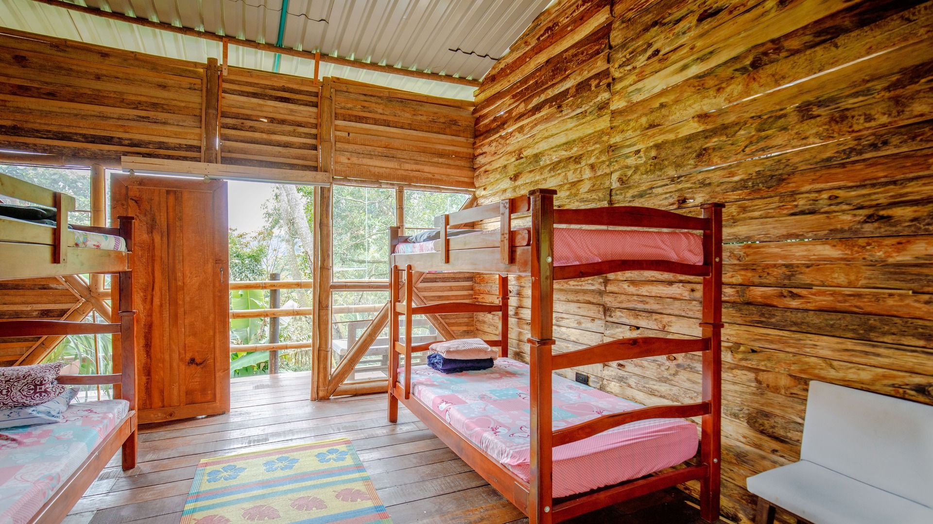 Una cabaña de madera con literas, una mesita y un banco.