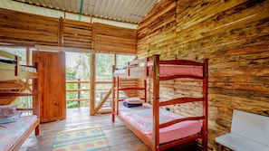 A wooden cabin with bunk beds, a small table, and a bench. - Reserva Colina de Cristal (Caldas)