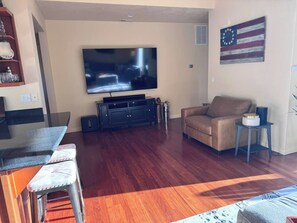 A living room with a flat-screen TV, a sofa, a coffee table, and a dining area with chairs. - The Oakway - Close to UO Campus + Autzen + Golf! (Eugene)