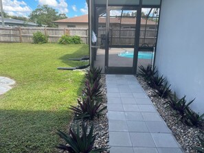 A backyard with a patio leading to a house, a wooden fence, and a swimming pool. - The Sunshine Sanctuary 
Entire home Private Pool & 2 Bedroom and 2 FullBathrooms (Sarasota)