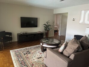 A living room with a flat-screen TV, a sofa, a coffee table, and a patterned rug. - The Sunshine Sanctuary 
Entire home Private Pool & 2 Bedroom and 2 FullBathrooms (Sarasota)