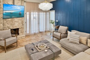 Un salon avec un mur en pierre, un téléviseur, une cheminée et un mur recouvert de panneaux bleus.