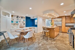 Une cuisine moderne avec des meubles blancs, un îlot central et un coin repas comprenant une table ronde et des chaises.
