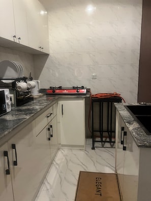 A compact kitchen with a gas stove, a refrigerator, and a sink. - Perfect 2-bedroom apartment in Akure for a relaxing stay (Akure)