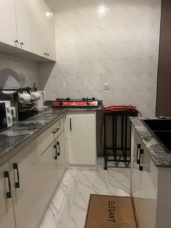 Een functionele keuken met een gasfornuis, een koelkast en een spoelbak.