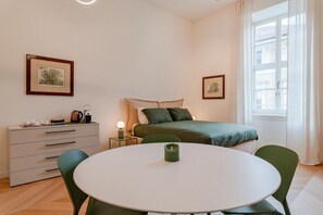 A bedroom with a bed, bedside table, lamp, and a dresser. - Benny Suite is a renovated studio apartment at Via Alfieri 16b, in the heart of Turin.Elegant, bright, and meticulously detailed, it combines modern design and comfort.You'll find a cozy living/sleeping area, a fully equipped kitchenette, and a bathroom  (Turin)