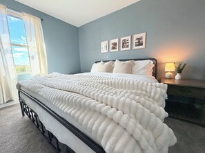 A bedroom with a bed, a nightstand, a lamp, and framed pictures on the wall.