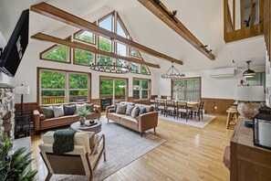 A spacious living area with high ceilings, large windows, and a dining area. - Poconos Retreat: Sauna, Hot Tub, Fire Pit & Games (Lake Harmony)