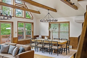 A dining area with a wooden table and chairs, a chandelier, and large windows with blinds. - Poconos Retreat: Sauna, Hot Tub, Fire Pit & Games (Lake Harmony)