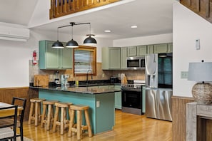 A modern kitchen with a central island, bar stools, stainless steel appliances, and a wooden ceiling. - Poconos Retreat: Sauna, Hot Tub, Fire Pit & Games (Lake Harmony)