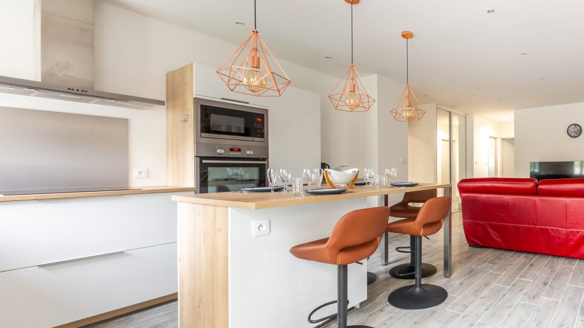Une cuisine moderne dotée d’un îlot central, de tabourets de bar et de luminaires suspendus.