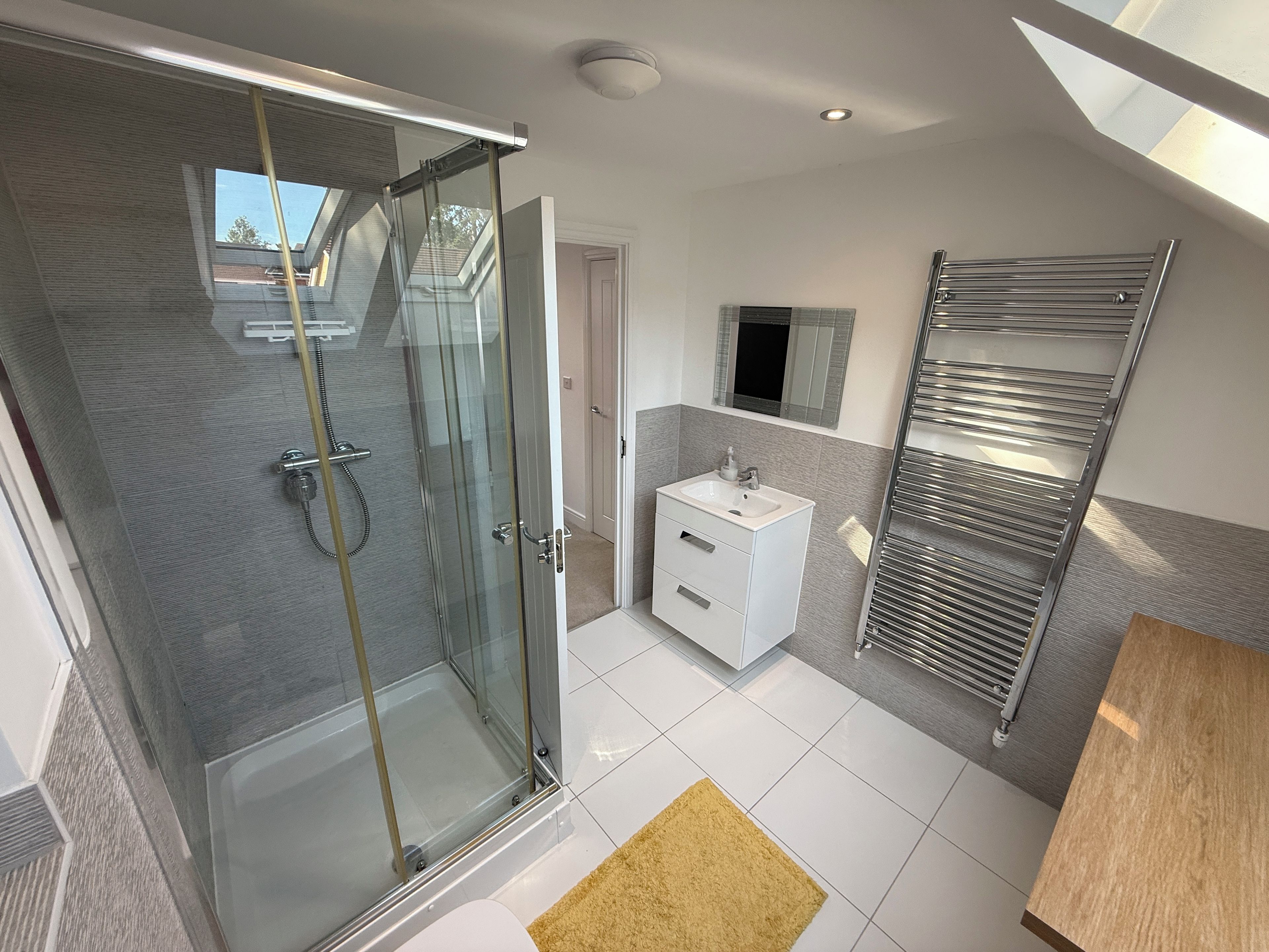 A modern bathroom with a glass shower enclosure, a white vanity, and a towel rack.