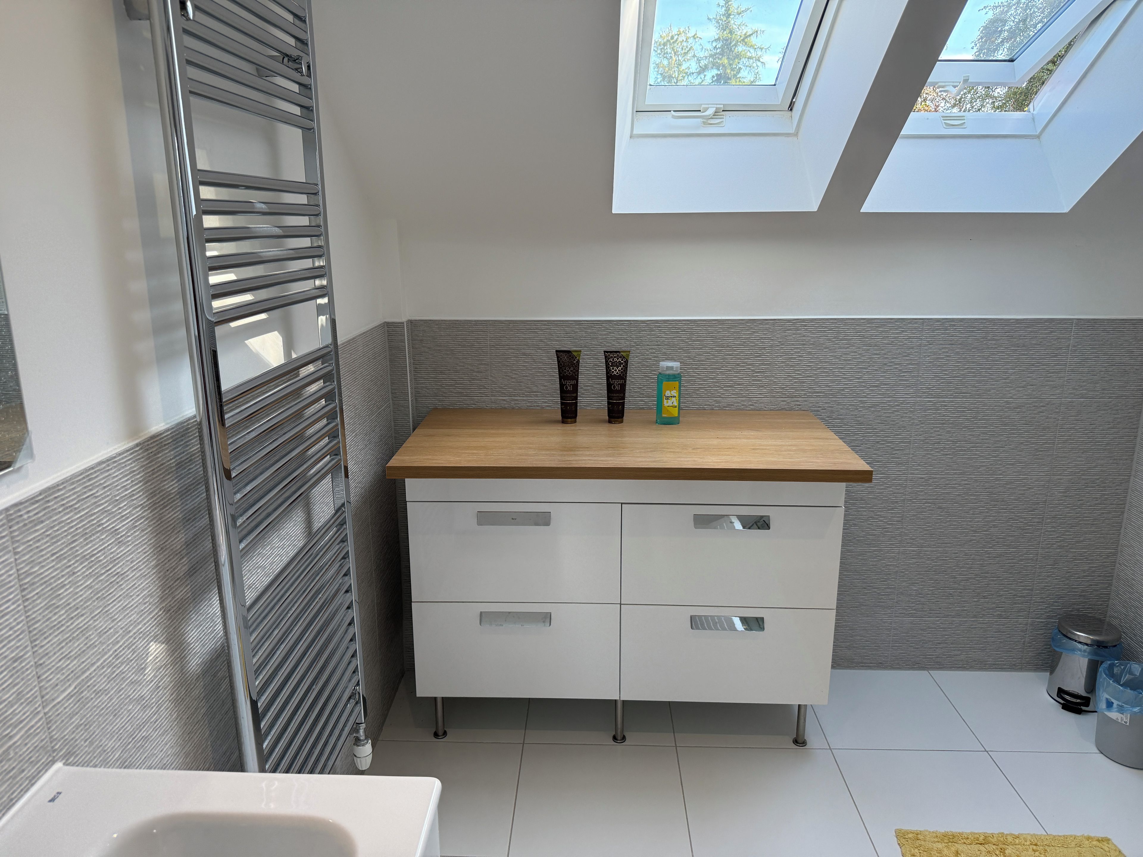 A modern bathroom with a skylight, a wooden countertop, and a white cabinet.