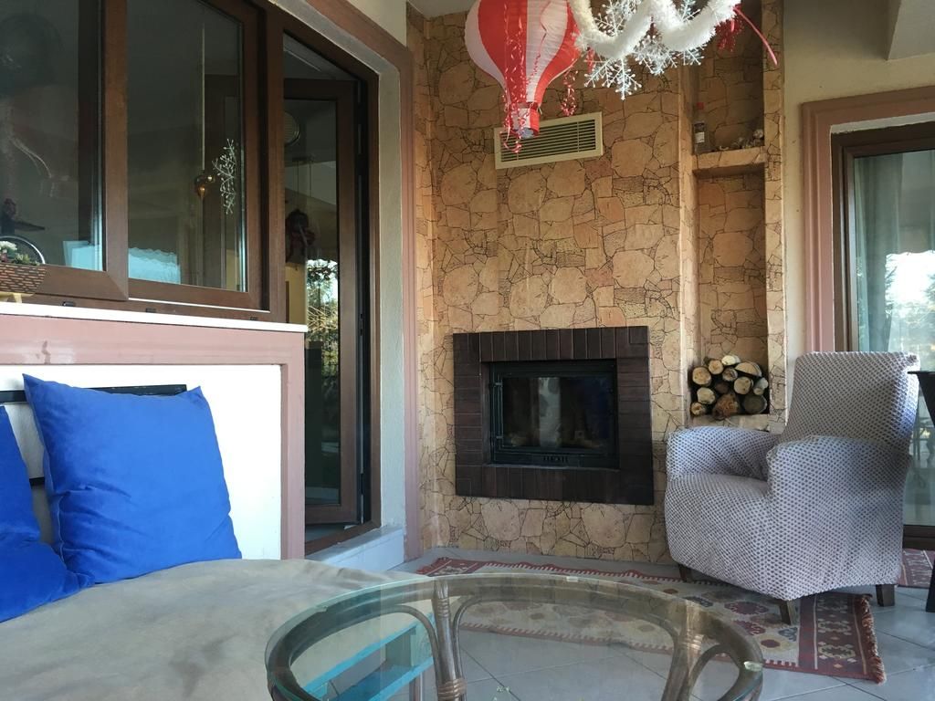 Una sala de estar con chimenea, un sofá con cojines azules y un sillón estampado.