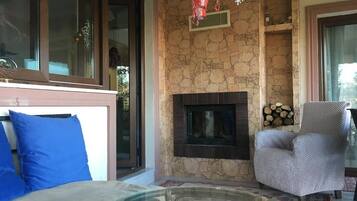 Una sala de estar con chimenea, un sofá con cojines azules y un sillón estampado.