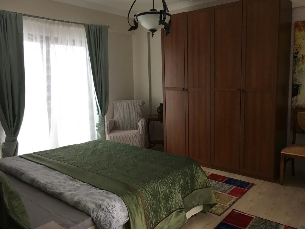 Un dormitorio con una cama, una silla, un armario y una ventana con cortinas.