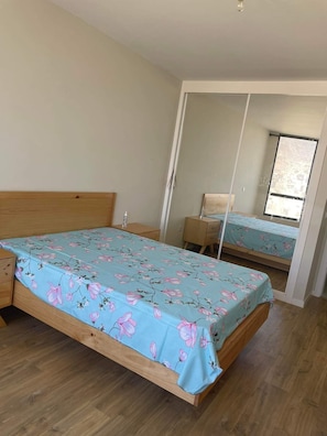 A bedroom with a bed, a nightstand, a mirror, and a window. - Adorable 2-bedroom apartment in vibrant Mindelo perfect for relaxing stay (Mindelo)