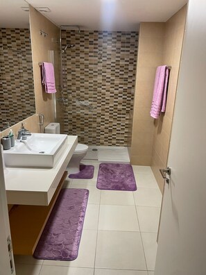 Une salle de bain avec douche, toilettes et lavabo.