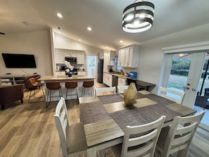A modern kitchen with white cabinets, a central island, and a dining area with a table and chairs. - Beautiful House in Sebring! Sleeps 8 (Sebring)