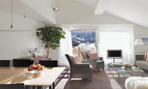 Een moderne woonkamer met een eethoek, een groot raam met uitzicht en een flatscreen televisie.