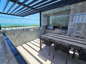 An outdoor patio with a grill and seating area overlooking a body of water. - New Listing (Cabedelo)