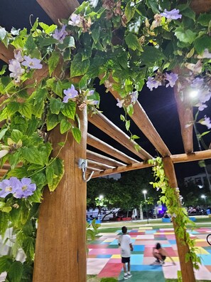 En pergola af træ med slyngplanter og blomster.