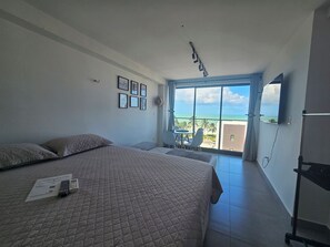 Et hotelværelse med en stor seng, et skrivebord og en balkon med havudsigt.