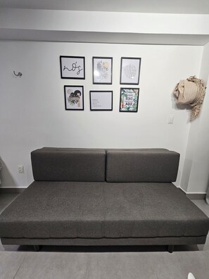 A modern living room with a grey sofa, a wall-mounted light switch, and six framed artworks. - New Listing (Cabedelo)