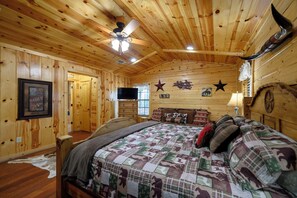 Ein Schlafzimmer in einer Holzhütte mit einem Bett, einem Deckenventilator und Wanddekorationen, darunter Sterne und Tierfiguren.