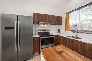 Eine moderne Küche mit Edelstahlgeräten, Holzschränken und einem großen Fenster mit Vorhängen.