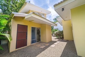 A modern house with a flat roof, a sliding glass door, and a gravel driveway. - Private Pool Villa • Gated • Near Playa Negra (Provincia de Guanacaste)