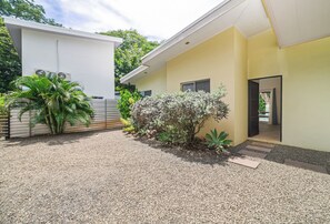 A modern building with a gravel driveway, a small garden with various plants, and a door leading to the entrance. - Private Pool Villa • Gated • Near Playa Negra (Provincia de Guanacaste)