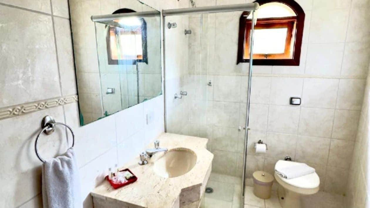 Ein Badezimmer mit einer Duschkabine, einem Waschbecken mit Spiegel und einer Toilette.