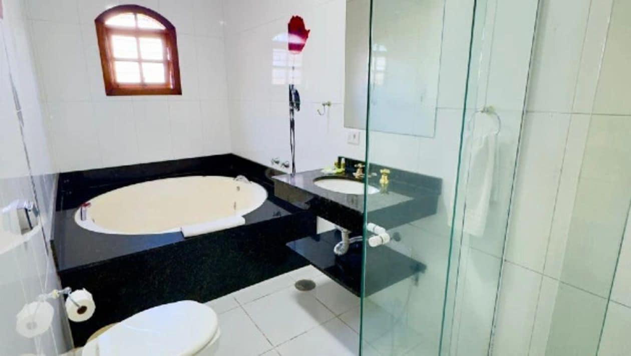 Un baño con bañera, inodoro y ducha con mampara de vidrio.