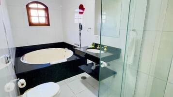 Un baño con bañera, inodoro y ducha con mampara de vidrio.