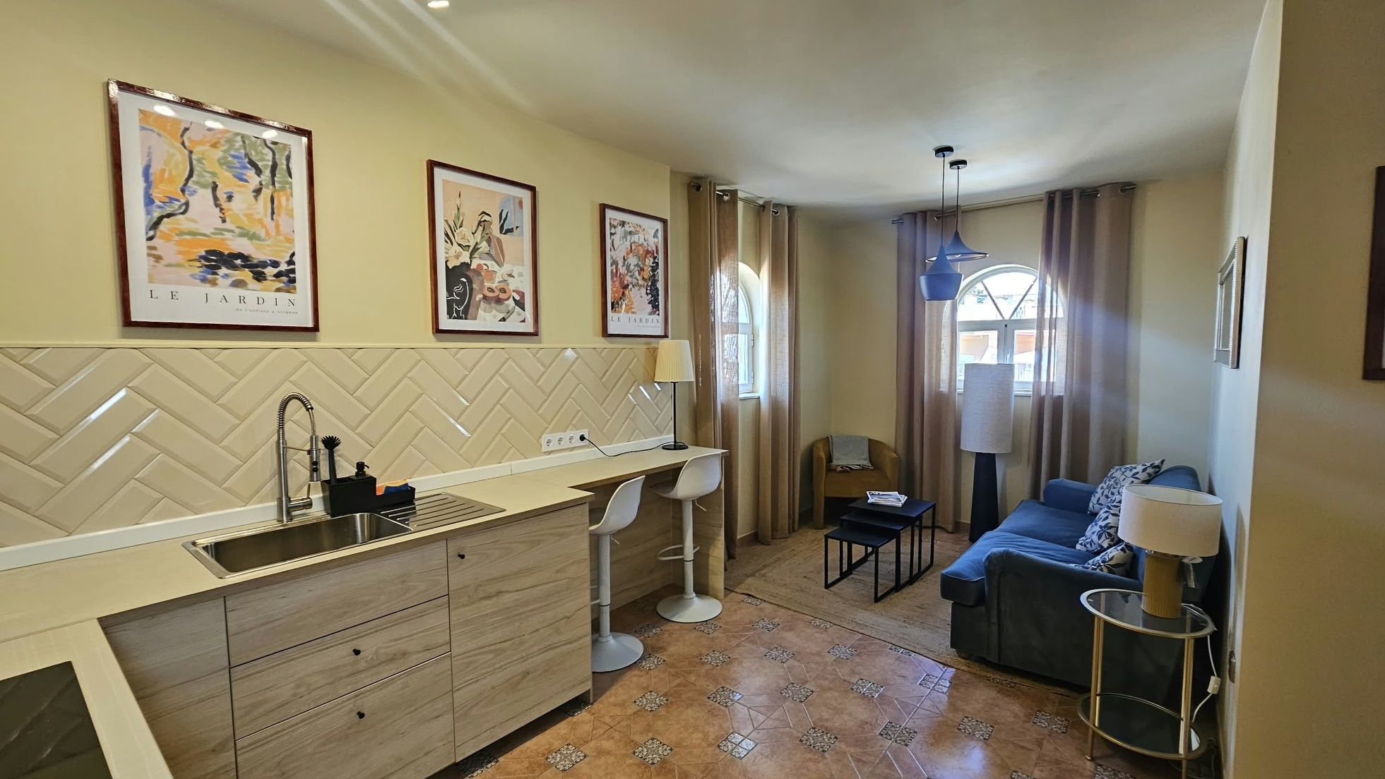 A compact living space with a kitchenette, a dining area, and a seating area with a sofa and a small table.