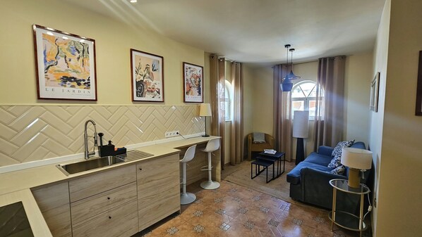 A compact living space with a kitchenette, a dining area, and a seating area with a sofa and a small table. - Charming Apartment with Terrace & Views in Málaga (Málaga)