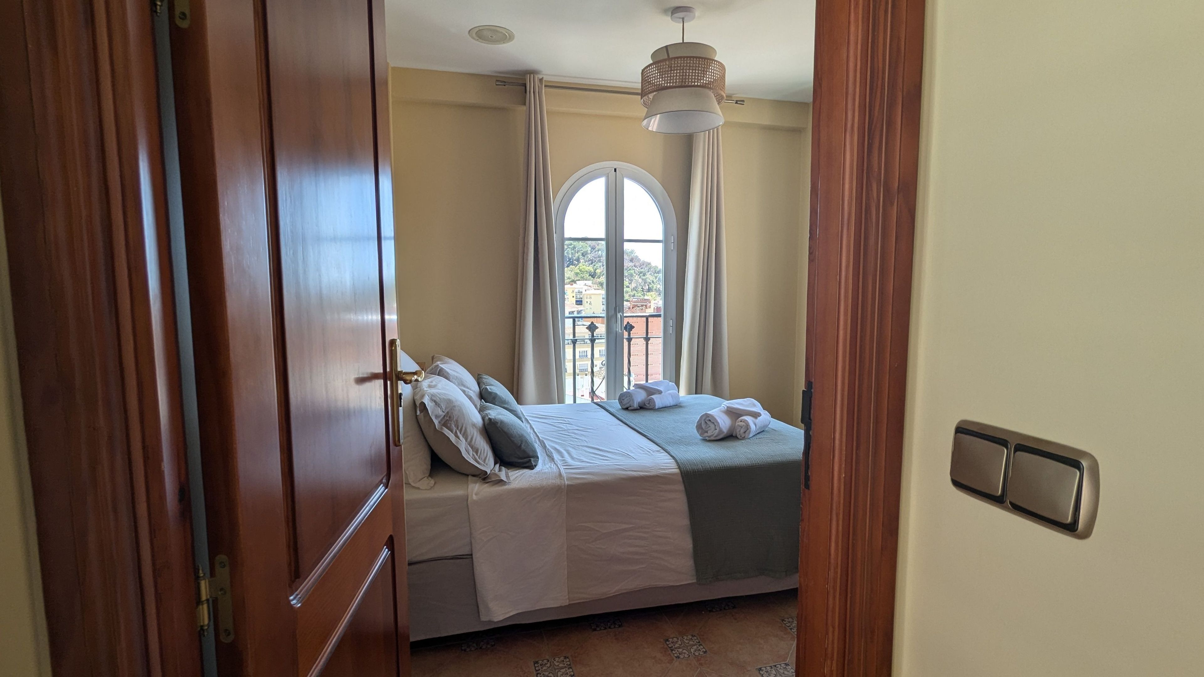 Een slaapkamer met een bed, een raam, een deur en een plafondlamp.